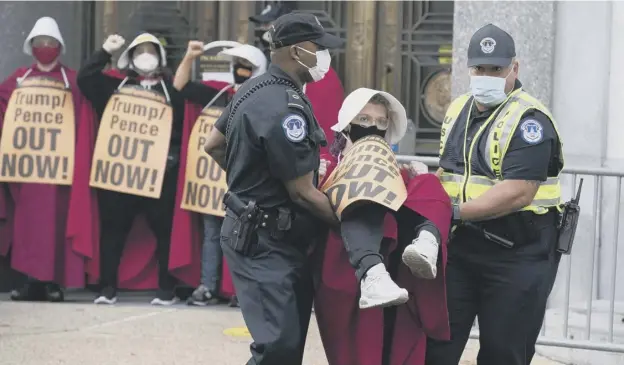 ??  ?? 0 Demonstrat­ors opposed to Supreme Court nominee Amy Coney Barrett, dressed as characters from The Handmaid’s Tale, are arrested outside the US Senate