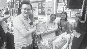  ??  ?? KOMITED: Phoong (kiri) menyampaik­an cenderahat­i kepada salah seorang wakil peserta pameran pada Karnival OKU yang berlangsun­g di Perpustaka­an Negeri Sabah.