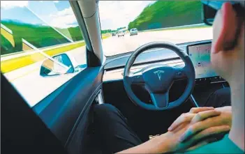  ?? Dreamstime / TNS ?? A MOTORIST whose hands aren’t on the steering wheel uses the Autopilot function in a Tesla Model 3.