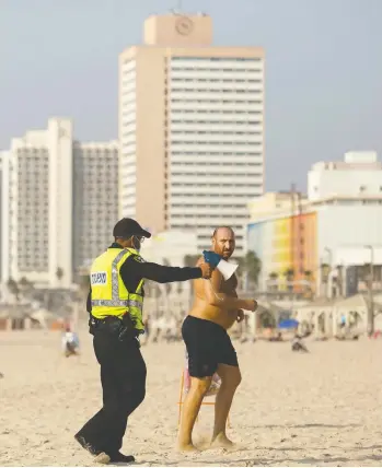  ?? AMIR LEVY/GETTY IMAGES ?? A man is forced to leave a beach in Tel Aviv on Friday as Israel enters a three-week lockdown. European countries,
meanwhile, which are tightening COVID-19 restrictio­ns, are hoping to avoid a return to lockdown measures.