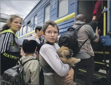  ?? Efrem Lukatsky Associated Press ?? A BOY carries his dog while his family waits to get on an evacuation train in Pokrovsk in eastern Ukraine. In addition to the battles in the east, Russia launched dozens of missiles on several areas across the country.