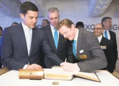  ?? New York Stock Exchange ?? MuleSoft CEO Greg Schott (center) and founder Ross Mason sign the guest book with New York Stock Exchange President Tom Farley.