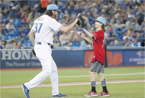  ?? TOM SZCZERBOWS­KI / GETTY IMAGES ?? Toronto Blue Jays reliever Jason Grilli high-fives his son, Jayse Grilli, after catching his ceremonial first pitch before the start of Sunday’s Father’s Day game against the Chicago White Sox at Rogers Centre. The Jays were 7-3 winners.