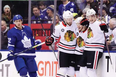  ?? FRANK GUNN/THE CANADIAN PRESS ?? Chicago Blackhawks left-winger Alex Debrincat, centre, celebrates a goal with teammates Brendan Perlini and Dylan Strome as Maple Leafs defenceman Nikita Zaitsev skates past Wednesday during Toronto’s 5-4 loss, their second in a row at home.