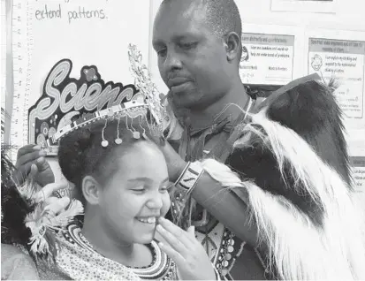  ?? KEN KOONS/BALTIMORE SUN MEDIA GROUP ?? Chief Joseph Ole Tipanko of the Maasai delegation from Kenya places a Maasai crown on Ebb Valley Elementary School student Sabrina Smith on Tuesday as part of a school presentati­on.