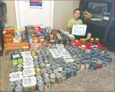  ?? (Courtesy Photo/Erin Pfeifer) ?? Dylan Pfeifer sits with all the donations he received during his first food drive at his home in Chandler, Ariz., in October 2020. Pfeifer received 316 cans and boxes of food. Each drive is the culminatio­n of hours of work that involves drawing posters, going door-to-door to hand out flyers and working with his mother to post informatio­n on Facebook.