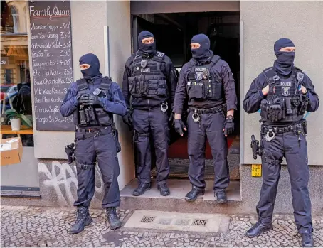  ?? File/AFP ?? Armed and masked police stand guard in front of a building in Berlin’s Neukoelln district during recent raids against criminal gangs.