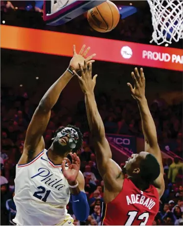  ?? DREW HALLOWELL / GETTY IMAGES ?? 76ers masked center Joel Embiid, who had 19 points and 12 rebounds, takes a shot over Heat backup center Bam Adebayo on Tuesday at Wells Fargo Center. Philadelph­ia won the series 4-1.