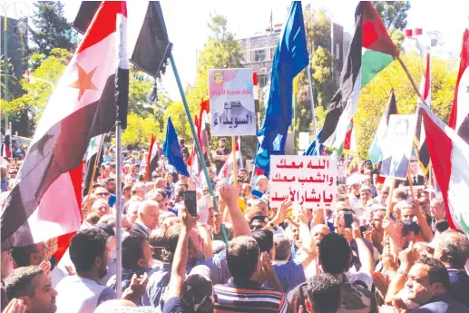  ?? (SANA/Reuters) ?? SUPPORTERS OF Syria’s President Bashar Assad carry his pictures and Syrian flags during a demonstrat­ion in the mainly Druze city of Sweida on Wednesday. Stormy demonstrat­ions against Assad have also taken place there over the past week.