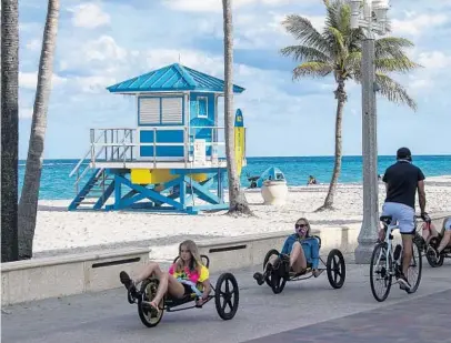  ?? MICHAEL LAUGHLIN/SUN SENTINEL ?? People pass a lifeguard tower on Hollywood beach on Tuesday. The city has spent more than $2 million on 21 new stands and is on the verge of spending $700,000 more to buy eight more towers — six lifeguard stands and two first aid stations.