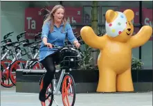  ?? EAMONN AND JAMES CLARKE / FOR CHINA DAILY ?? A woman uses a Mobike bicycle in Manchester, the United Kingdom, in this file photo.