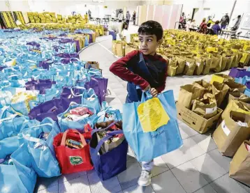  ?? Steve Gonzales / Staff photograph­er ?? Dilan Dalal, 11, carries bags of food at the East Spring Branch Food Pantry, which provided Thanksgivi­ng meals on Tuesday to 1,200 families. Story on page A3.