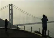  ?? ERIC RISBERG — THE ASSOCIATED PRESS ?? People take pictures of the Golden Gate Bridge as smoke from wildfires covers the San Francisco skyline Tuesday in this view near Sausalito.