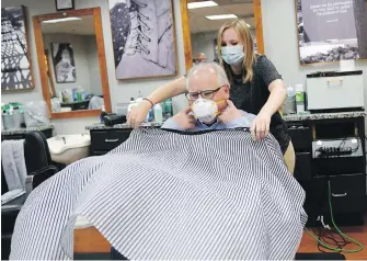  ??  ?? Mask-wearing Minnesota Gov. Tim Walz gets his hair cut by Erin Diede in St. Paul, Minnesota. Until recently, masks were viewed with unease in western cultures.