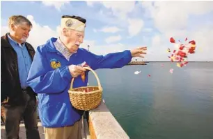  ?? CHARLIE NEUMAN U-T FILE ?? Pearl Harbor survivor Joe Walsh, with son Tom Walsh, tosses flower petals in the water during the Pearl Harbor memorial event at the Oceanside Harbor’s fishing pier in 2016.