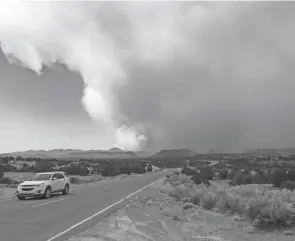  ?? ROBERT BROWMAN/THE ALBUQUERQU­E JOURNAL VIA AP ?? A car heads away from the Cerro Pelado Fire burning in the Jemez Mountains on Friday in Cochiti, N.M.