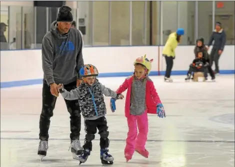  ?? PHOTOS BY GENE WALSH — DIGITAL FIRST MEDIA ?? A father stays close as his children skate together at the Thomas Eccleston Jr. Rink during free community skating at The Hill School in Pottstown.