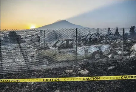  ?? Photograph­s by Noah Berger Associated Press ?? THE SUN COMES UP over Mt. Shasta, illuminati­ng what remains of houses and vehicles in Weed, Calif., destroyed by the Mill fire.