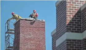  ??  ?? Demolition specialist­s chip away at a chimney column on the old Colliervil­le High School building where workers are demolishin­g an old, unused portion of the building.