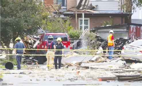  ?? MIKE HENSEN / POSTMEDIA NEWS ?? Fire officials in London, Ont. survey the scene after a car being driven the wrong way crashed into a home at 450 Woodman Avenue and caused a huge natural gas leak and massive explosion earlier this week. Seven people were injured and 100 area homes evacuated.