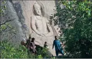  ?? ABDUL MAJEED / AGENCE FRANCE-PRESSE ?? Pakistani visitors walk past the seventh-century rock sculpture of the Buddha of Swat carved into a mountain in Pakistan.