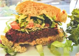  ?? PHOTO BY CAMERON MORGAN ?? Cashew’s Beet Burger comes with lettuce and tomato topping. The side dish of garlicky kale is optional, but is a perfect pairing with the mild burger.