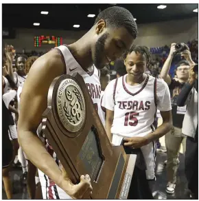  ?? (Arkansas Democrat-Gazette/Thomas Metthe) ?? Pine Bluff’s Jordan Harris holds the state championsh­ip trophy while he celebrates with teammates on Thursday following the Zebras’ 67-51 victory over Lake Hamilton in the Class 5A boys state championsh­ip game at Bank OZK Arena in Hot Springs. More photos at arkansason­line.com/310boys5ab­b/.