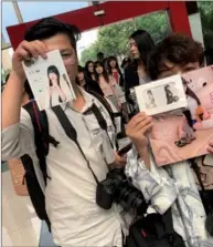  ??  ?? Fans Chen Xiao (left) and Su Liang show photos and posters of their idol Yaorenmao that they bought during the competitio­n in Hangzhou.