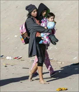  ?? ANDRES LEIGHTON — THE ASSOCIATED PRESS ?? A migrant mother carries her child while walking barefoot toward the border fence after crossing the Rio Grande in their attempt to enter into El Paso, Texas, from Ciudad Juarez, Mexico on Wednesday.