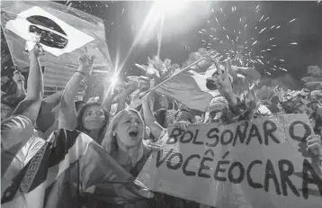  ?? BUDA MENDES/GETTY ?? Supporters of far-right president-elect Jair Bolsonaro celebrate Sunday in front of his house in Rio de Janeiro.