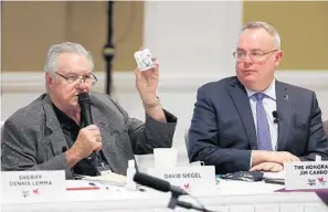  ?? STEPHEN M. DOWELL/ORLANDO SENTINEL ?? David Siegel, left, holds a bottle of Narcan, a drug used to treat opioid overdoses, as White House Office of National Drug Control Policy Director Jim Carroll watches in Orlando on Tuesday.