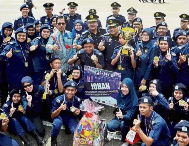  ??  ?? Drilling for gold: Wan Ahmad Uzir (in a batik shirt) next to Johor Education Department deputy director Azman Adnan and JPJ cadets from SMK Pasir Gudang celebratin­g their win at a foot drill competitio­n at the camp in Johor Baru.