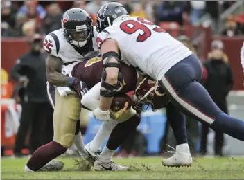  ?? AP PHOTO/MARK TENALLY ?? Washington Redskins quarterbac­k Alex Smith (11) ankle is injured as he is sacked by Houston Texans defensive end J.J. Watt (99) and Houston Texans strong safety Kareem Jackson (25) during the second half of an NFL football game, on Sunday, in Landover, Md.