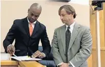  ?? LOIS SOLOMON/SUN-SENTINEL ?? Mack Bernard signs his mayoral paperwork, assisted by Steve Weiss of the Palm Beach County Clerk’s Office.