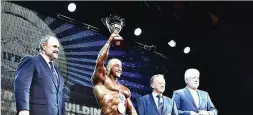  ??  ?? JAKUB CSONTOS/EASTLABS Iran’s Morteza Roshan-zamir (2nd L) holds aloft the overall world bodybuildi­ng champion trophy at the 2018 IFBB World Bodybuildi­ng Championsh­ips in Benidorm, eastern Spain, on November 12, 2018.