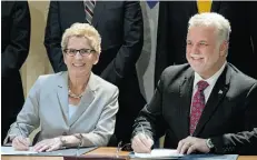  ?? JACQUES BOISSINOT/ THE CANADIAN PRESS ?? Ontario Premier Kathleen Wynne, left, and Quebec Premier Philippe Couillard, sign an agreement on cap-and-trade Monday in Quebec City.