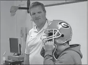  ?? Spencer Lahr / Rome News-Tribune ?? Coosa High School football coach and teacher Todd Wheeler, also a former University of Georgia and NFL player, lets Alto Park Elementary School fifth-grader Jose Vasquez try on his UGA helmet during a presentati­on for the elementary school’s first...