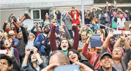  ?? Amy Osborne / Special to The Chronicle ?? Top: The crowd reacts as the fog lifts in time for the eclipse to be viewed at Chabot Space & Science Center in the Oakland hills, where the large gathering was more like a rock concert than a science activity.