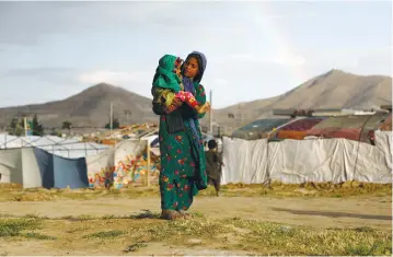  ?? (Omar Sobhani/Reuters) ?? AN AFGHAN girl carries a child at a refugee camp on the outskirts of Kabul in 2019.