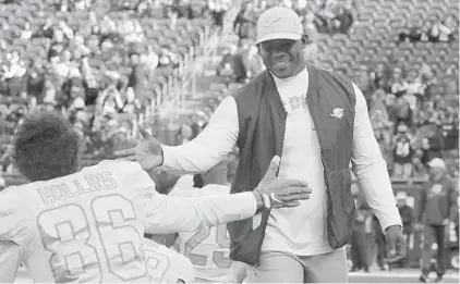  ?? CHARLES KRUPA/AP ?? Dolphins coach Brian Flores, right, greets receiver Mack Hollins as the team warms up before a game on Dec. 29 in Foxborough, Mass.