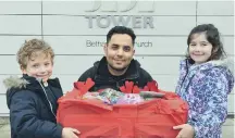  ??  ?? Samuel Errington , five, and Abby Bell, seven, offer hamper donations to refugee Miaad Hajianfar.