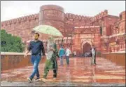  ?? PTI ?? Tourists protect themselves from rain at Red Fort in Agra.
