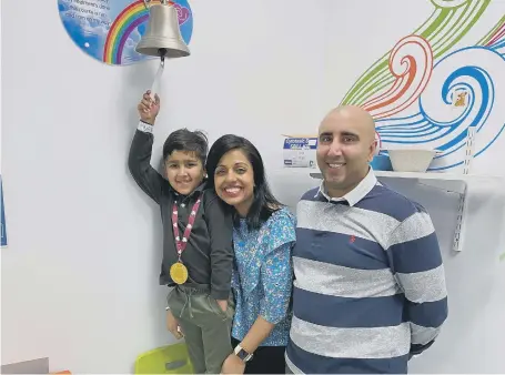  ??  ?? All smiles from Saahib Randhawa and his parents, mum Gurpreet and dad Manprit, as he rings the bell.