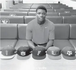  ?? VIA RIVALS / TWITTER ?? Valdosta (Georgia) Lowndes quarterbac­k Jacurri Brown with the hats of his top five schools, including the Miami Hurricanes, in front of him during a video interview with Rivals. Brown will be joining the Hurricanes in their Class of 2022.