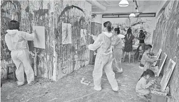  ?? — AFP photo ?? Patrons creating watercolou­r and acrylic paintings at Splat Paint House in Singapore.