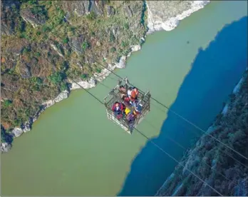  ?? ZHANG ZHI / FOR CHINA DAILY ?? Residents use an aerial cable bridge to cross the Jinsha River, a major tributary of the Yangtze River, in Butuo county, Sichuan province, on Friday. This is the last cable bridge in use across the river. A new bridge is expected to be put into use...