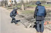  ?? ?? Bomb disposal officers remove part of a Russian Grad missile lodged in a road in Kharkiv, north-east Ukraine