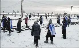  ?? MACIEK NABRDALIK / NEW YORK TIMES ?? Visitors wearing Israeli flags tour the Auschwitz-Birkenau Memorial and Museum on Sunday in Oswiecim, Poland. The nation’s president signed a bill outlawing accusation­s that Poles were complicit in the Holocaust.