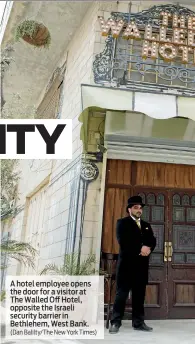  ?? (Dan Balilty/The New York Times) ?? A hotel employee opens the door for a visitor at The Walled Off Hotel, opposite the Israeli security barrier in Bethlehem, West Bank.