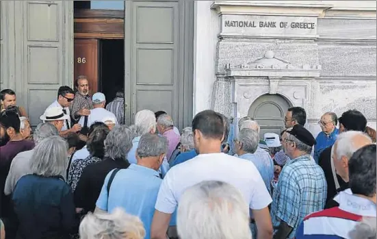  ?? THANASSIS STAVRAKIS / AP ?? Una multitud entra en una oficina bancaria, ayer en Atenas